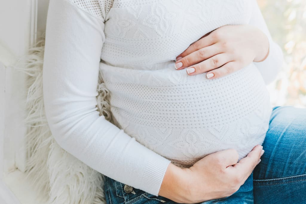 Pregnant woman in white knit sweater — pregnancy week guide