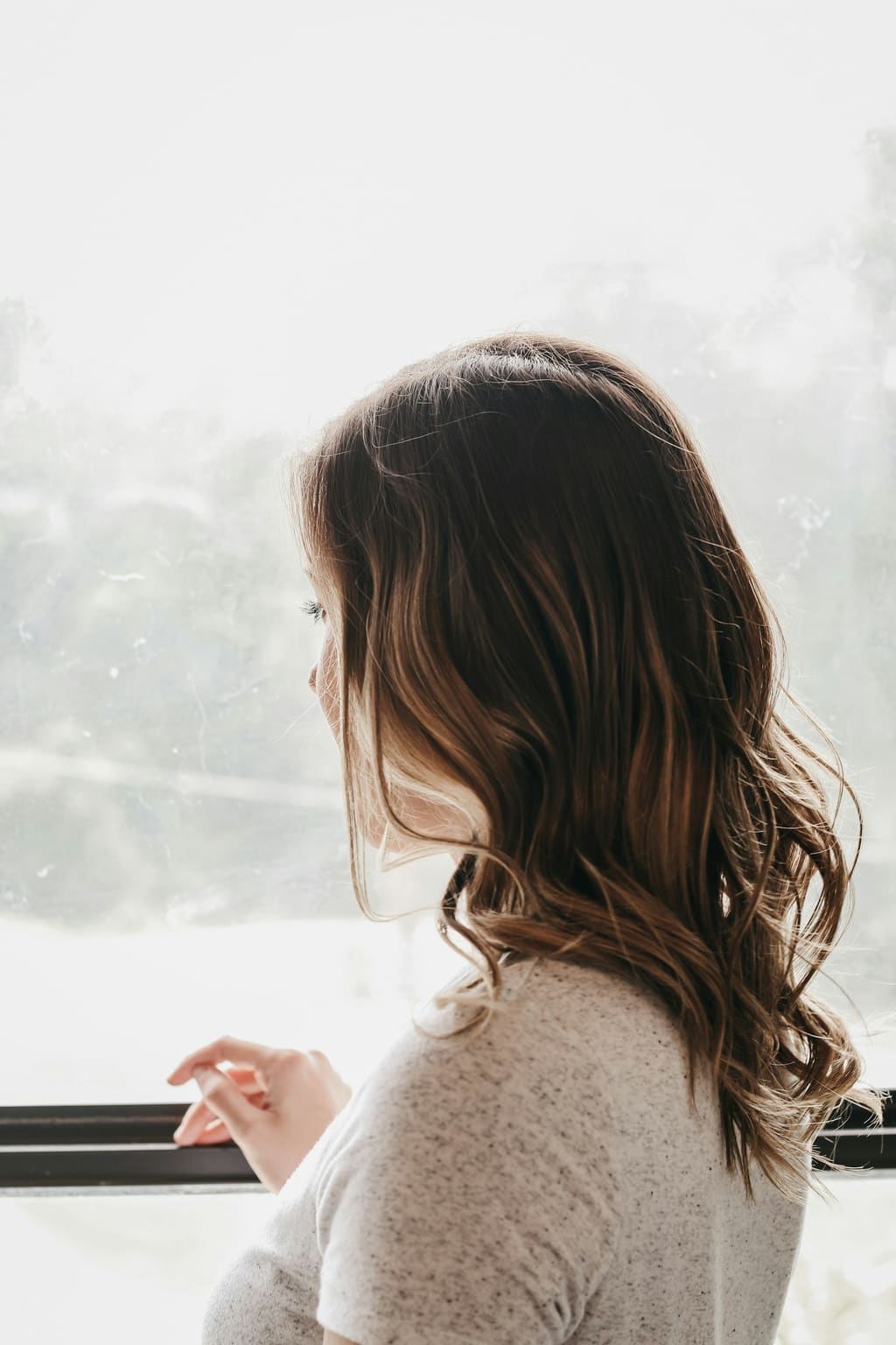 Woman looking out of a window in soft daylight — can you be pregnant and still have a period