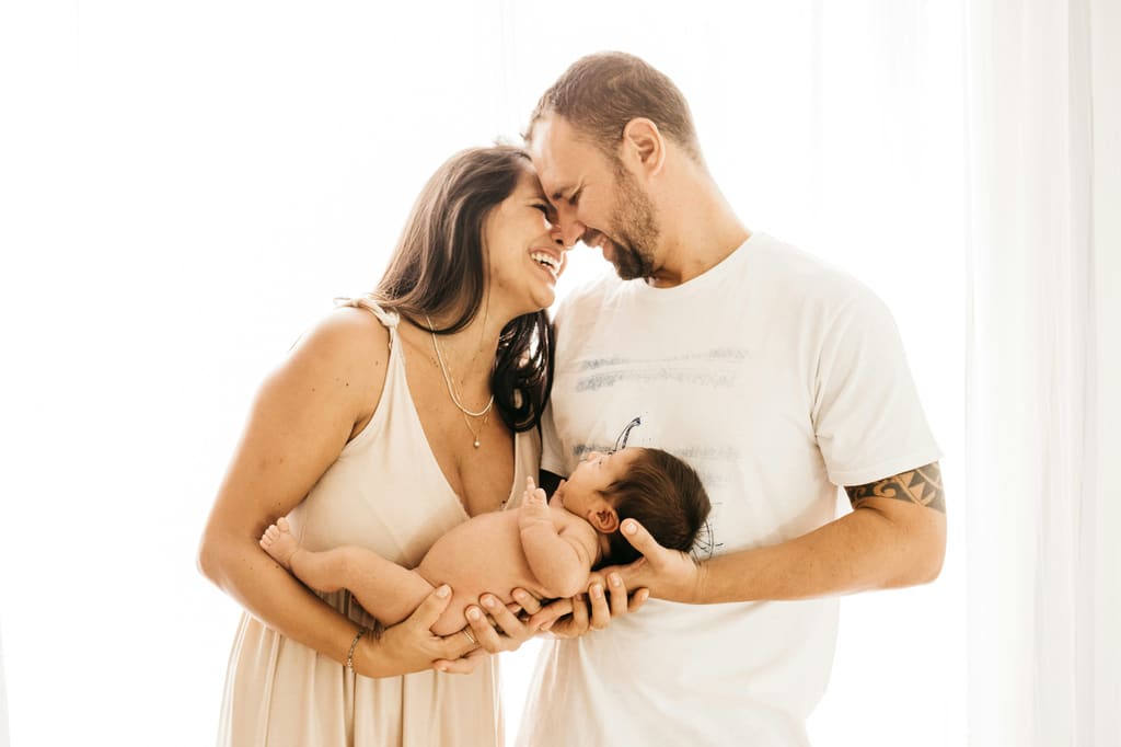 Parents holding their newborn in soft window light — pregnancy weight gain by trimester