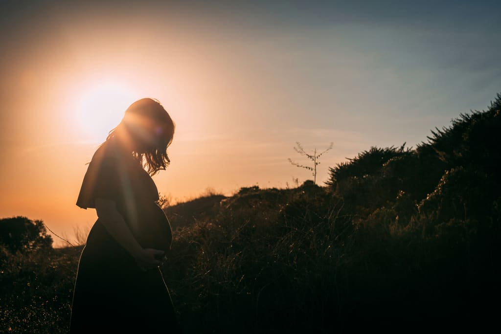 Pregnant woman cradling her belly in natural light