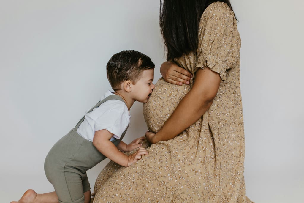 Toddler kissing his mother's pregnant belly — Chinese gender predictor 2026